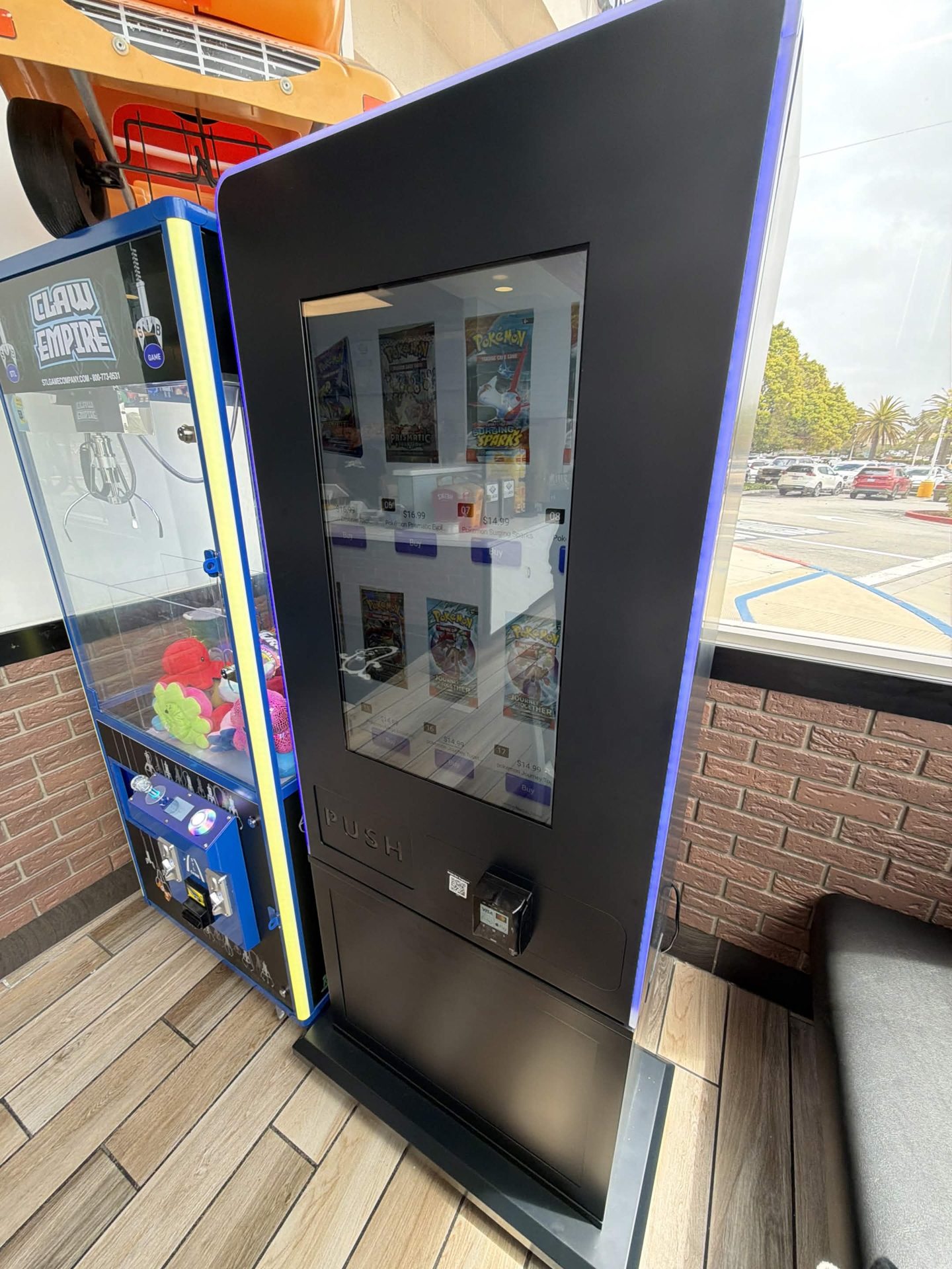 Card vending machine placed beside a claw machine in a sunny venue